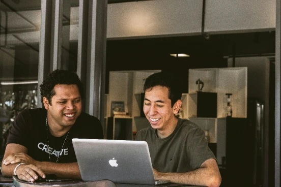 friends laughing looking at a laptop